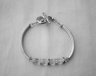 May include: A silver bracelet with a toggle clasp and clear rectangular beads.