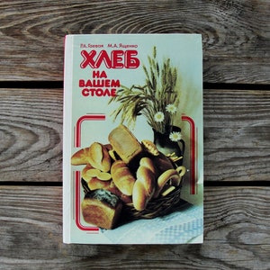 May include: A vintage cookbook titled "ХЛЕБ НА ВАШЕМ СТОЛЕ" (Bread on Your Table) with a red border and a photo of various breads and wheat stalks on the cover.