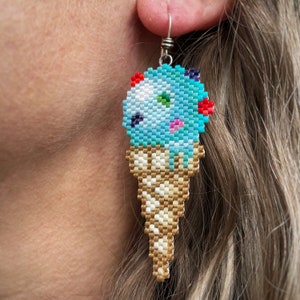 Boucles d'oreilles en forme de gouttes de crème glacée Goody Gum, tressées avec des perles de rocaille Miyuki Delica, sur des crochets de boucles d'oreilles en argentium 93,5 français dans une boîte en papier kraft.