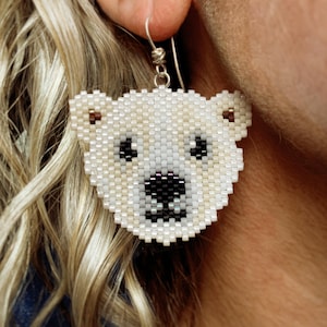 Boucles d'oreilles ourson polaire, tissées avec des perles de rocaille Miyuki Delica, sur des crochets de boucle d'oreille français en argentium 93,5 dans une boîte en papier kraft.