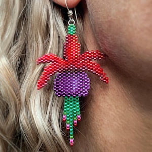 Boucles d'oreilles fuchsia, tissées avec des perles de rocaille Miyuki Delica, sur des crochets de boucles d'oreilles en argentium 93,5 français dans une boîte en papier kraft.