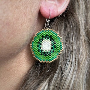 Boucles d'oreilles kiwi, tissées avec des perles de rocaille Miyuki Delica, sur des crochets de boucles d'oreilles en argentium 93,5 français dans une boîte en papier kraft.