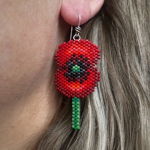 Boucles d'oreilles coquelicot, tissées avec des perles de rocaille Miyuki Delica, sur des crochets en argentium 93,5 français dans une boîte en papier kraft.