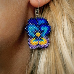 Boucles d'oreilles pensée, tissées avec des perles de rocaille Miyuki Delica, sur des crochets de boucle d'oreille en argentium 93,5 dans une boîte en papier kraft.