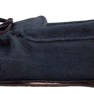 May include: A pair of dark blue suede moccasins with a leather sole and a decorative bow on the top.
