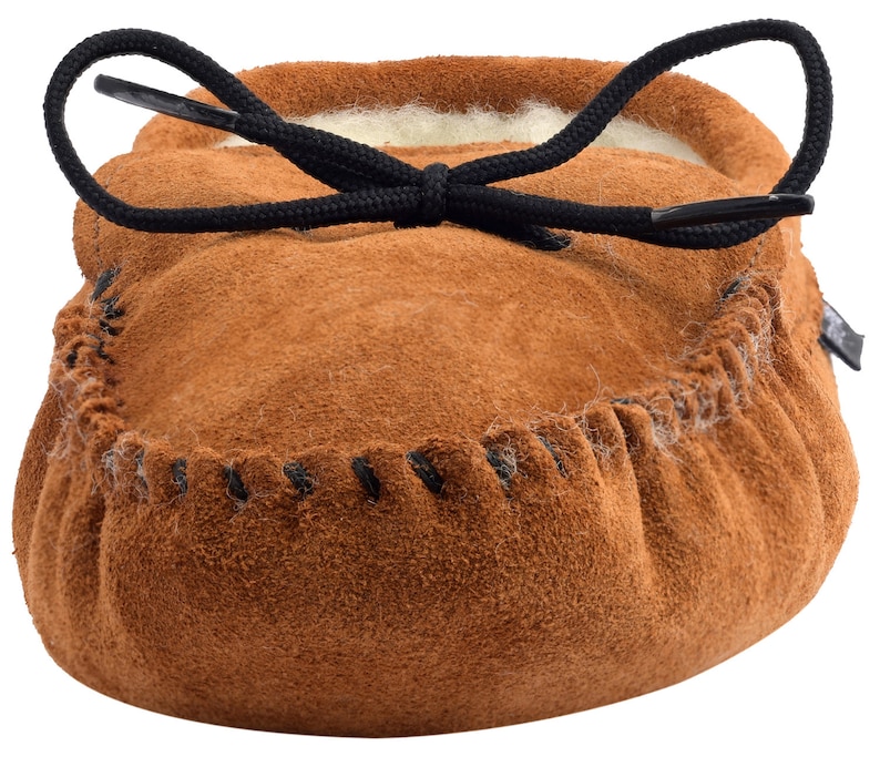 May include: Brown suede moccasin slippers with a black drawstring closure and a white fleece lining.