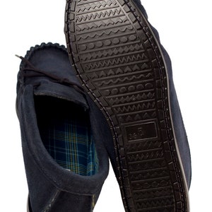 May include: A pair of dark blue suede moccasins with a plaid lining. The soles are black rubber with a textured pattern.