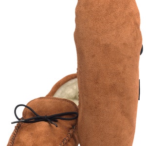May include: A pair of brown suede moccasins with a black leather tie. The moccasins have a soft, fuzzy lining and a stitched seam around the edge.