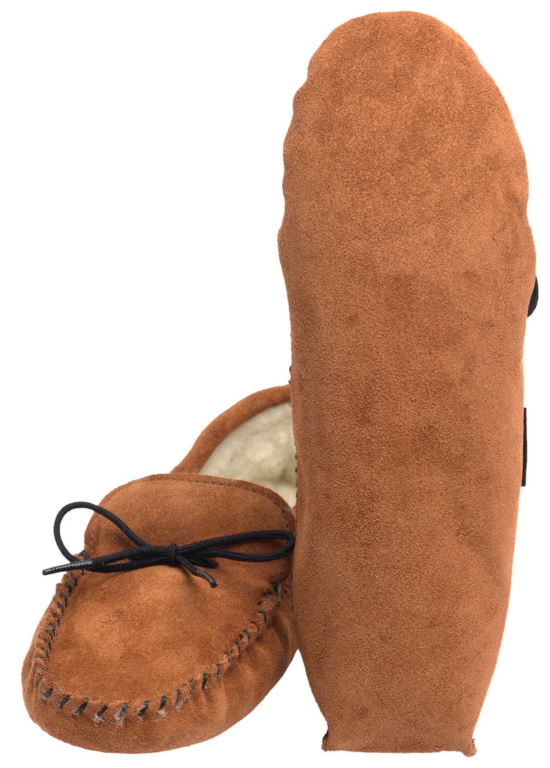 May include: A pair of brown suede moccasins with a black leather tie. The moccasins have a soft, fuzzy lining and a stitched seam around the edge.