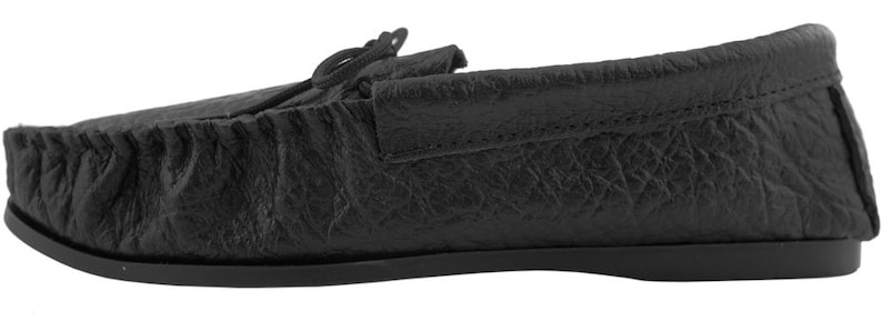 Op de afbeelding: Zwarte leren mocassinslippers met een eenvoudig ontwerp. De slippers hebben een zachte, comfortabele uitstraling en gevoel.