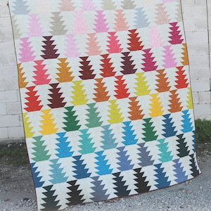 May include: A colourful quilt featuring a repeating pattern of stylised fir trees in shades of pink, orange, yellow, green, blue, and grey. The quilt measures 203cm x 229cm. The word "Conifer" is printed on the bottom right.