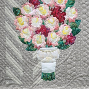 May include: A quilt block featuring a bouquet of pink, white, and red roses in a white vase with a bow. The block is titled "16th and Baltimore, Block 5: Roses and Cockscombs, ECQ 16B05, 18" x 18" ".