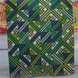 May include: A green, yellow, blue and white quilt with a geometric pattern. The quilt is labelled "Pacific Coast Highway" and "ECQ 0415" and measures 54" x 63".