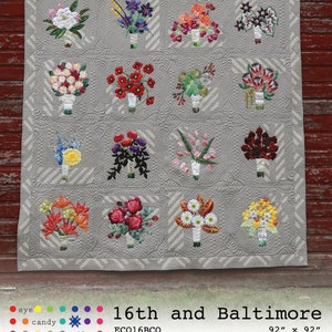 May include: A grey quilt featuring embroidered floral bouquets in a grid design. Each bouquet showcases a unique arrangement of colourful flowers. The quilt measures 234 cm x 234 cm. The text "16th and Baltimore" is displayed.