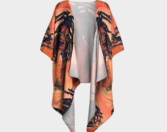 Puede incluir: Una prenda estilo kimono con frente abierto, que presenta un diseño artístico. La obra de arte representa un retrato con rastas, en tonos cálidos de naranja, marrón y negro. La tela cae suelta, mostrando el diseño completo.