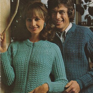 May include: Two people wearing knitted cardigans. The woman is wearing a teal cardigan with a zipper and pockets. The man is wearing a blue cardigan with a zipper.
