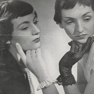 May include: Two women wearing black and white lace gloves. The woman on the left is wearing a pearl necklace and looking to the right. The woman on the right is looking down and has her chin resting on her hand.