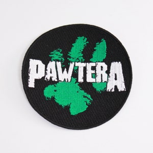 May include: A black and green embroidered patch with the word "PAWTERRA" in white lettering.