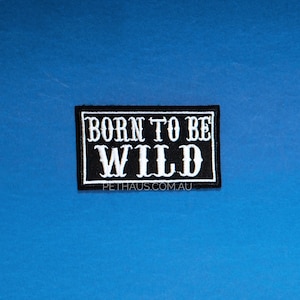 May include: A rectangular black patch with white text that reads "BORN TO BE WILD". The patch has a white border and is set against a blue background. The website address "PETHUAS.COM.AU" is printed at the bottom.