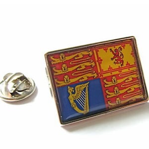 May include: A gold-coloured lapel pin featuring the Royal Standard of the United Kingdom. The pin has a red, yellow, and blue design with a lion and a harp.