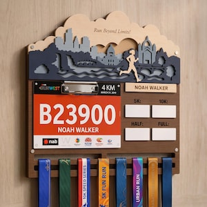 May include: A wooden medal display rack featuring a skyline cutout, a runner silhouette, and a metal clip holding a race bib with the text B23900 and NOAH WALKER. It includes a name plate for NOAH WALKER, four blank white rectangles for race times, and eight slots for hanging medals.