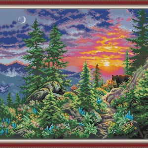 Könnte beinhalten: Ein gerahmtes Kreuzstich-Landschaftsbild zeigt einen Sonnenuntergang über einem Bergwald. Die Szene umfasst immergrüne Bäume, bunte Blumen, Felsen und zwei Bären. Der Himmel wechselt von Blau zu Orange und Rosa.