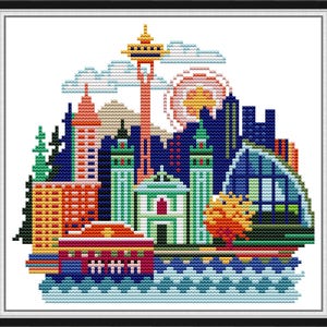 May include: A colorful cross-stitch pattern depicting a cityscape with buildings, a tower, clouds, and water. The buildings are in shades of blue, green, red, yellow, and orange. The tower is a tall, thin structure with a pointed top. The clouds are white and fluffy. The water is blue and wavy.