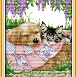 May include: A brown and white dog and a gray and white cat are sleeping on a pink and white patchwork quilt. The quilt is surrounded by green grass and purple flowers.