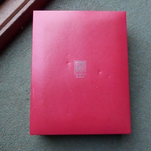 K&ouml;nnte beinhalten: Eine rote Box mit einem silbernen Logo, auf dem "Cr&eacute;ation Z&uuml;ndorf" steht.