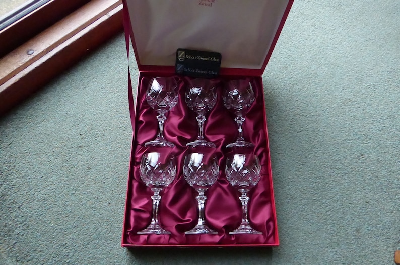 K&ouml;nnte beinhalten: Satz von sechs klaren Kristallweingl&auml;sern in einer mit rotem Samt ausgekleideten Schachtel. Die Schachtel tr&auml;gt ein Etikett mit der Aufschrift "Schott Zwiesel Glas".