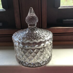 May include: A clear glass jar with a diamond pattern and a clear glass lid with a pointed top.
