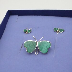 May include: A set of three silver butterfly jewelry pieces with green malachite inlays. The set includes a brooch and two earrings.
