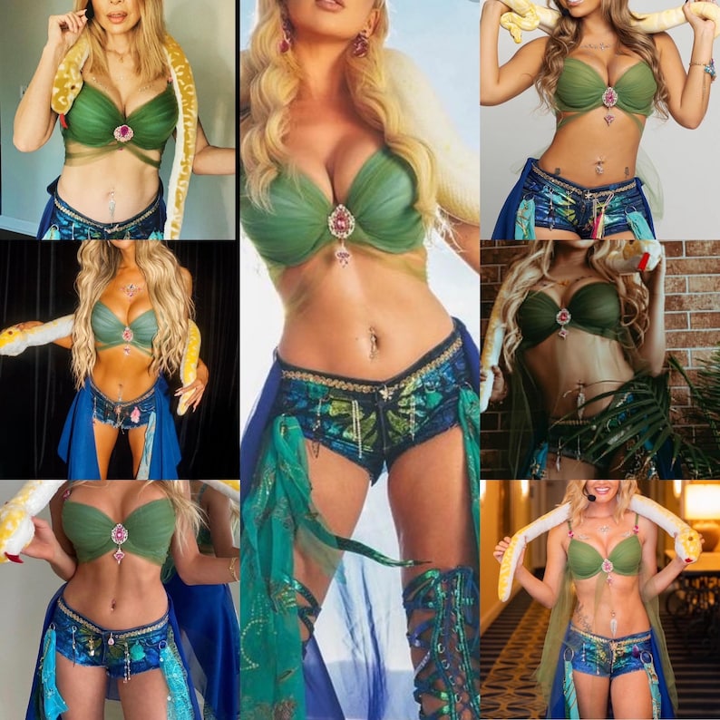 May include: A woman is wearing a green and blue bikini top and matching shorts. She is holding a snake in her hands. The snake is white and yellow. The woman is also wearing a necklace with a pendant. The background is a brick wall.