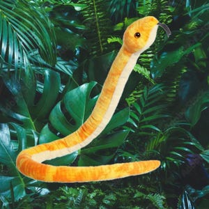 May include: A plush yellow snake toy with a white underside. The snake is curled up in a relaxed pose, with its head raised and its tongue sticking out. The snake is surrounded by green leaves.