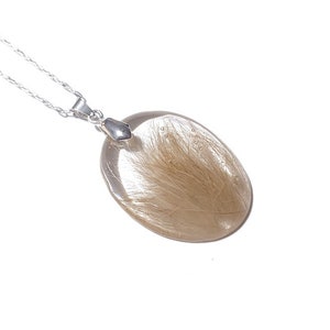 May include: A clear, oval-shaped pendant necklace with a silver chain. The pendant contains golden-brown inclusions, creating a unique, natural appearance. The necklace is displayed against a white background, highlighting the pendant's details.