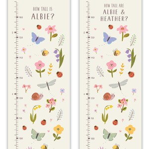 May include: Two colorful growth charts with a floral theme. The charts feature a ruler with measurements from 100 to 160 inches. The charts are decorated with butterflies, ladybugs, bees, flowers, and other nature-inspired elements. The text on the charts reads "How tall is Albie?" and "How tall are Albie & Heather?"