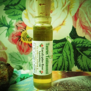 May include: A small glass bottle with a cork stopper filled with a light green liquid. The bottle has a white label with the text "Taurus Tantamount Eucalyptus-Rose Anointing Oil To relieve tension & promote comfort & stability For the peaceful & dignified".