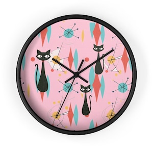 May include: A pink and black wall clock with a retro atomic age design featuring black cats and geometric shapes.
