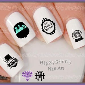 May include: White nail polish base with black nail art decals featuring The Haunted Mansion theme. Designs include three ghosts in a carriage, a framed text logo reading The Haunted Mansion, a crystal ball with a face, and a skeletal figure in a top hat.