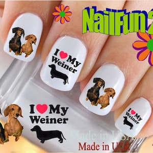 May include: Nail art decals featuring dachshund dogs. The decals have a black silhouette of a dachshund with the text "I love my Weiner" and a red heart. Other decals feature a photo of a dachshund.