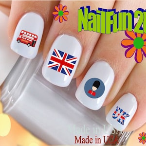 May include: White nail art with British motifs. Designs include a red double-decker bus, Union Jack flags, a Beefeater, and the letters "UK". The text "NailFun2U" is also visible.