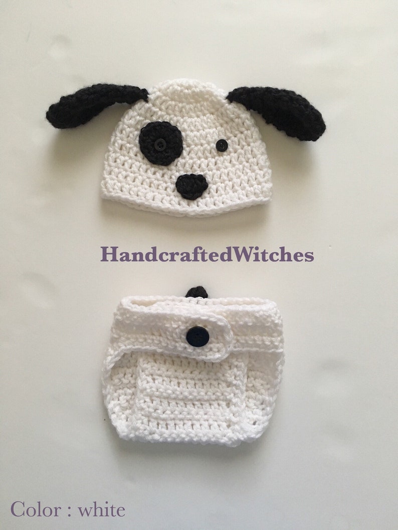 May include: White crocheted baby hat and diaper cover with black ears, nose, and eyes. The hat has a black spot on the side. The diaper cover has a black button. "HandcraftedWitches" is written on the image. "Color: white" is written at the bottom of the image.