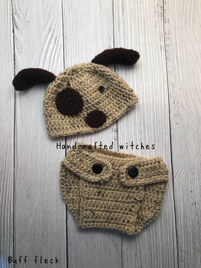 May include: A crocheted dog hat and diaper set in brown and beige with black buttons. The hat has brown ears and black eyes. The diaper has two black buttons on the front. The set is handcrafted by witches.