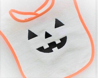 May include: White baby bib with an orange trim and a black embroidered jack-o'-lantern face.