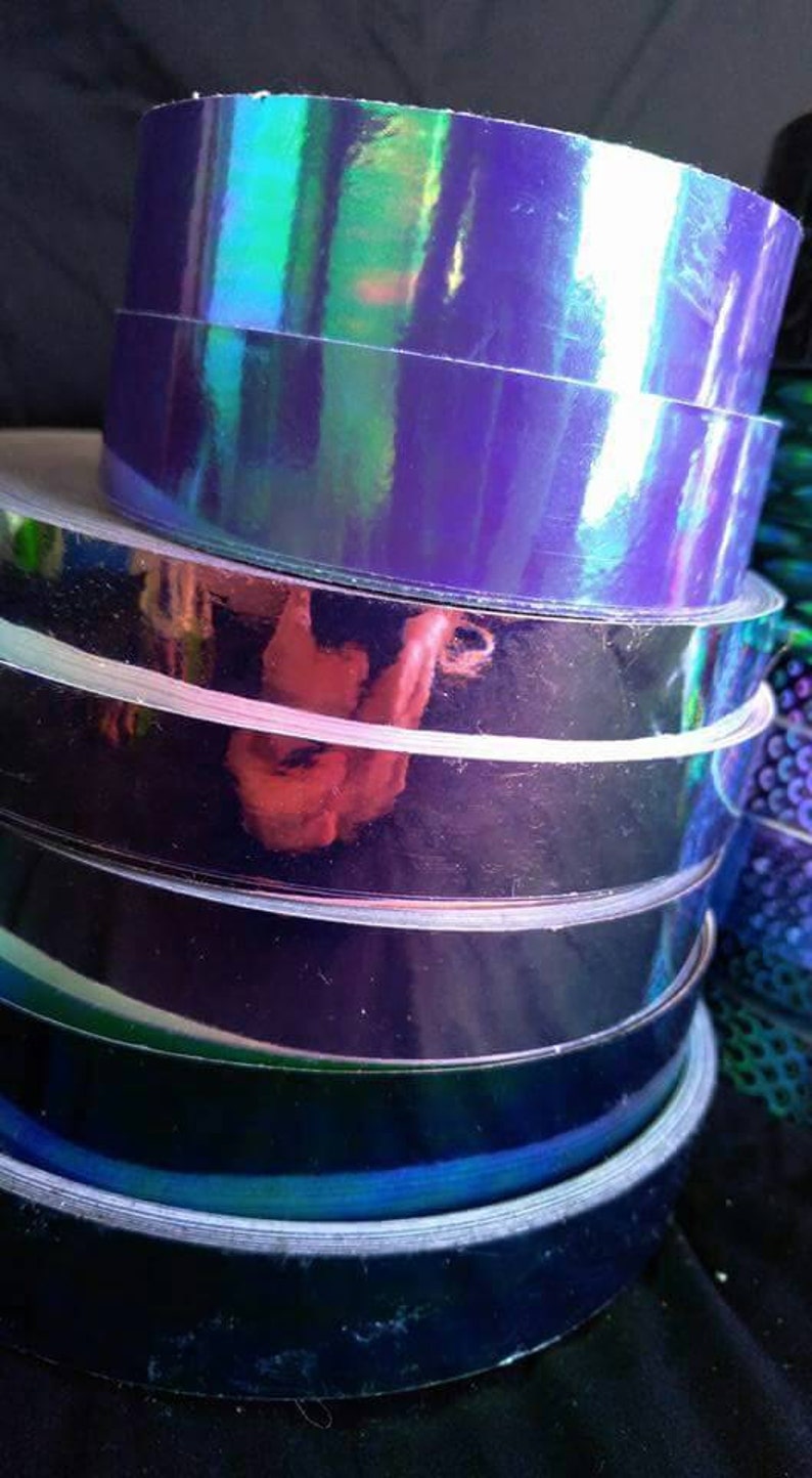 May include: A stack of iridescent purple and blue vinyl tape rolls. The tape is holographic and has a reflective finish.