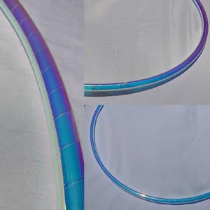 Puede incluir: Primer plano de un aro azul y blanco iridiscente. El aro est&aacute; hecho de pl&aacute;stico y tiene un acabado liso y brillante.