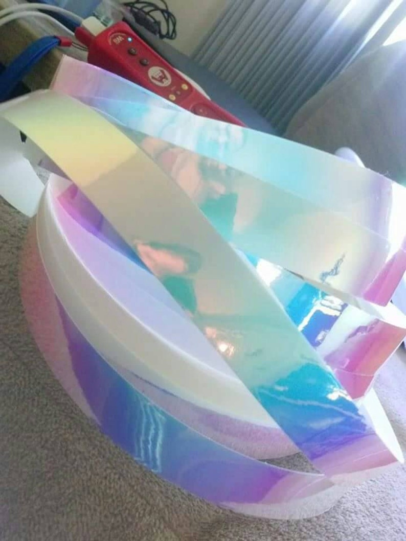 Puede incluir: Primer plano de rollos de cinta de vinilo hologr&aacute;fica iridiscente. La cinta es un arco&iacute;ris de colores, incluyendo rosa, azul, verde y morado.