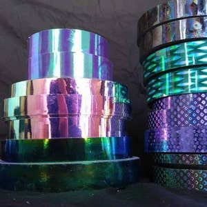 May include: Assortment of iridescent holographic tape rolls in various colors and patterns, including purple, green, and blue.