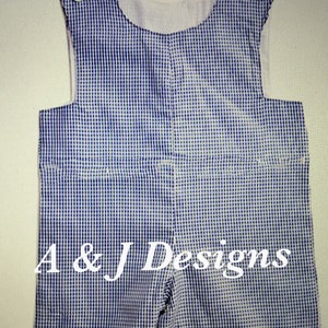 Peut inclure: Salopette bébé en vichy bleu et blanc avec boutons blancs et le texte "A & J Designs" sur le devant.