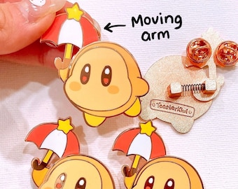May include: Three yellow and orange cartoon character pins with red and white umbrellas. The pins have a moving arm and a spring-loaded clasp on the back.